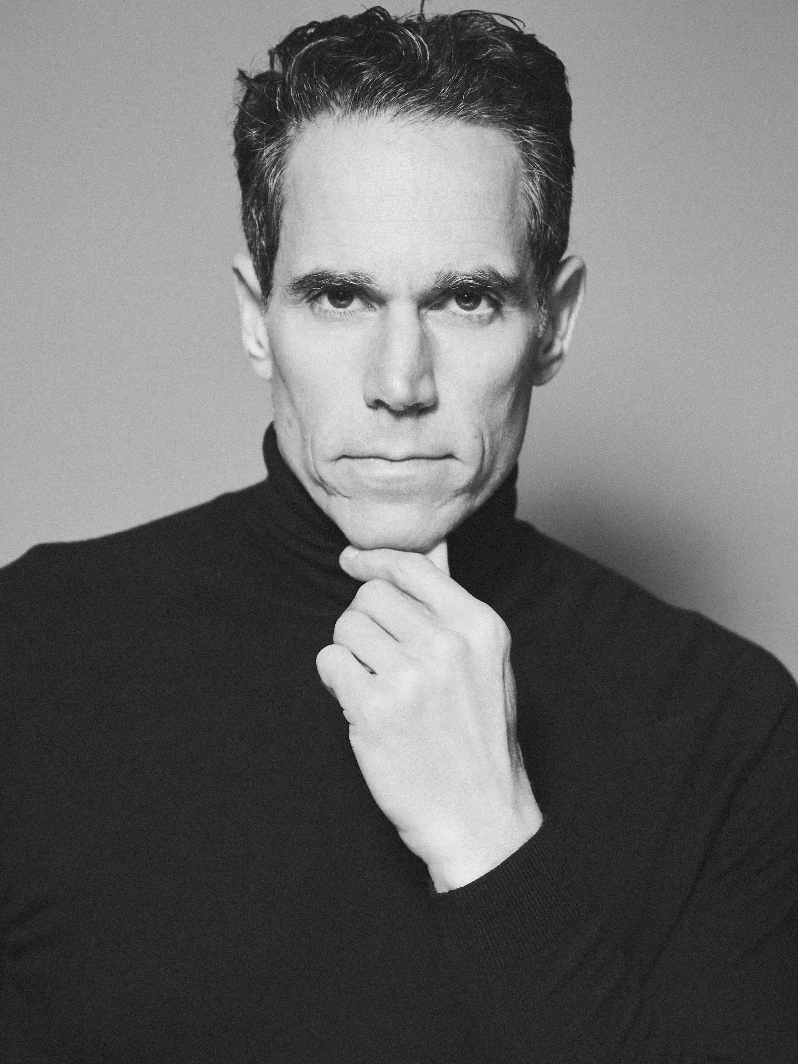 Franco Zuccoli in a black turtleneck, photographed in black and white